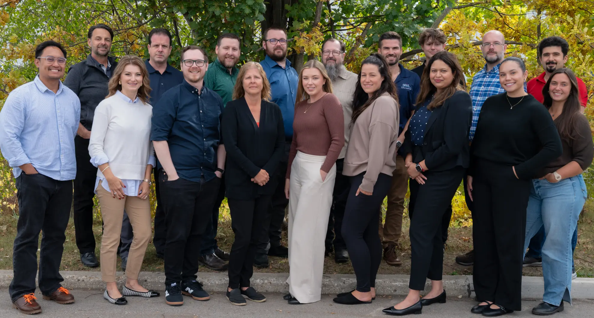 Group photo of 18 adults outdoors in fall setting – professional team or organization portrait