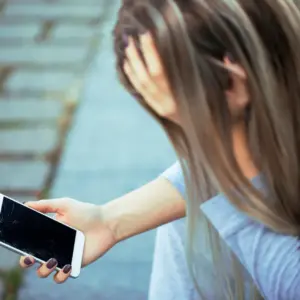 Reis Informática tech user frustrated by cracked smartphone screen, highlighting mobile device damage risks