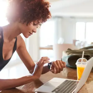 Reis Informatica image of a woman using a fitness tracker while working on a laptop.
